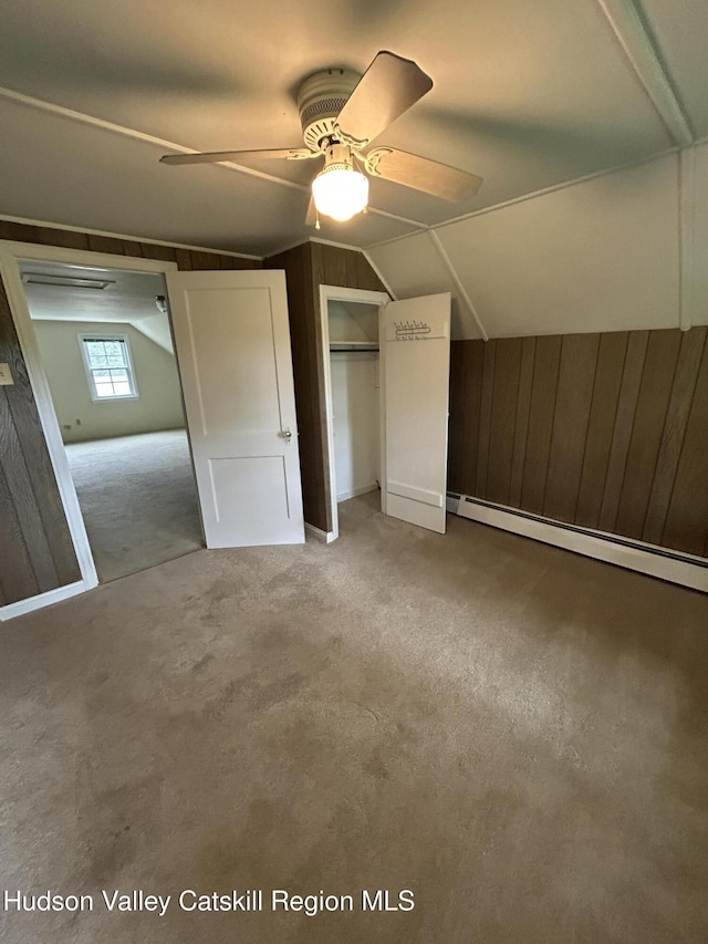 969 Blue Mountain Rd, Saugerties, NY 12477 - unfurnished bedroom with wooden walls, a baseboard heating unit, vaulted ceiling, carpet floors, and a ceiling fan
