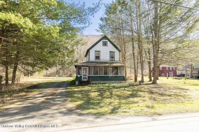 view of front of house with a front yard, a sunroom, driveway, and roof with shingles