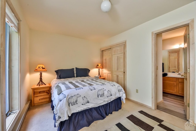 bedroom featuring light carpet, a closet, a baseboard heating unit, and baseboards
