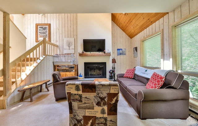 carpeted living room with lofted ceiling, wooden walls, a fireplace, and stairway