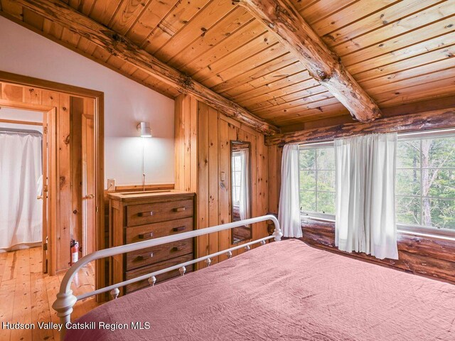 bedroom featuring vaulted ceiling with beams, wooden ceiling, wooden walls, and wood-type flooring