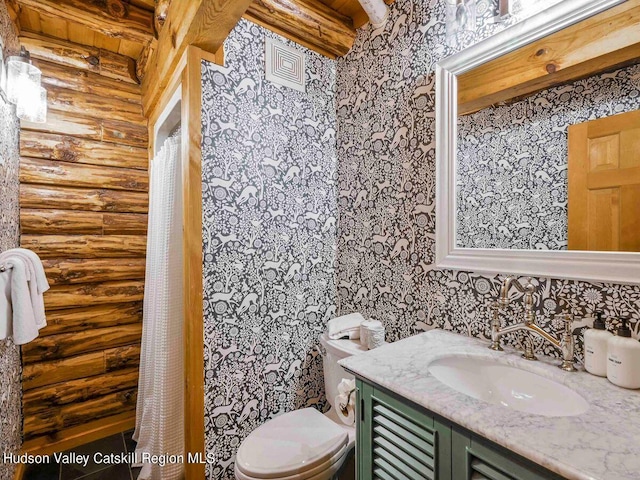 bathroom with vanity, toilet, and rustic walls