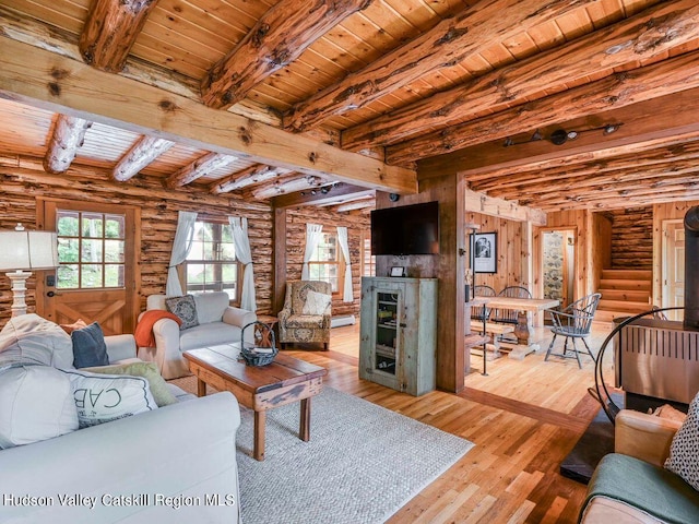 living room featuring beam ceiling, light wood-type flooring, log walls, and wooden ceiling