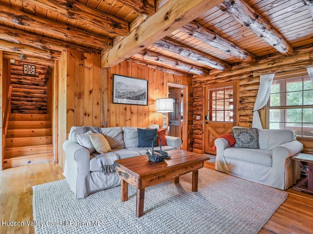 living room with beamed ceiling, light wood-type flooring, wooden ceiling, and log walls