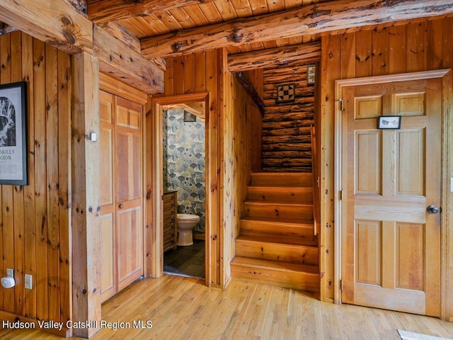 stairs featuring log walls, wood ceiling, and hardwood / wood-style flooring