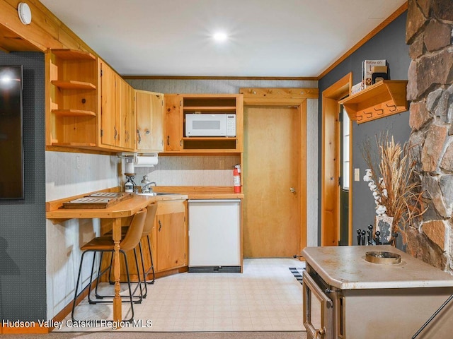 kitchen featuring white appliances, crown molding, and sink