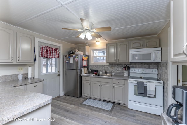 kitchen with decorative backsplash, plenty of natural light, white appliances, and sink