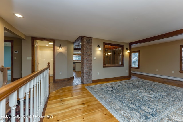 interior space featuring a baseboard heating unit, ornate columns, and wood-type flooring