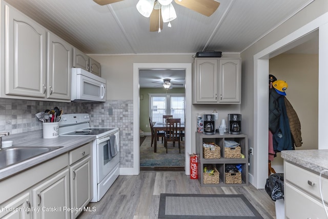 kitchen with white cabinetry, tasteful backsplash, white appliances, light wood-type flooring, and sink