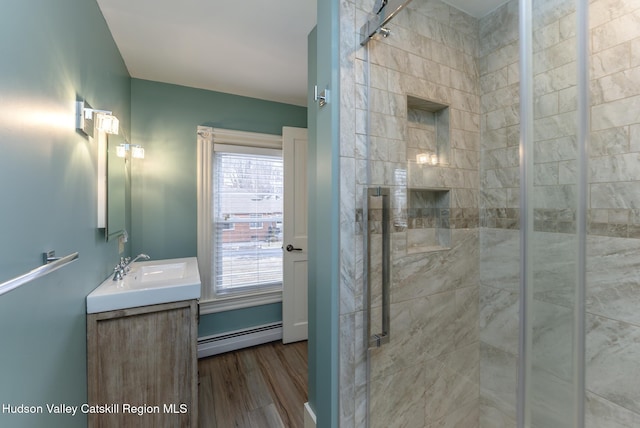 bathroom featuring a baseboard radiator, wood-type flooring, walk in shower, and vanity