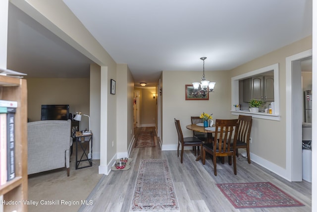 dining space with light hardwood / wood-style flooring and an inviting chandelier