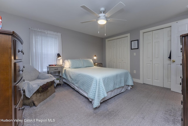 bedroom featuring ceiling fan, light carpet, and multiple closets