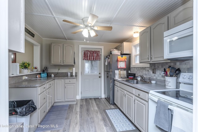 kitchen with sink, white appliances, gray cabinets, and light wood-type flooring