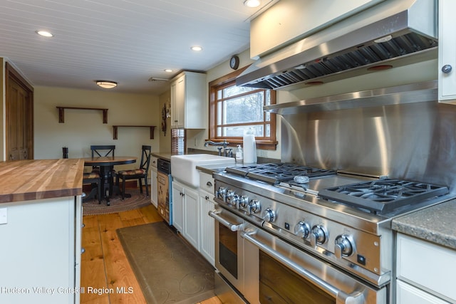 kitchen with white cabinetry, extractor fan, butcher block countertops, range with two ovens, and light hardwood / wood-style flooring