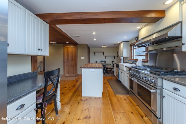 kitchen with double oven range, wood counters, and white cabinetry