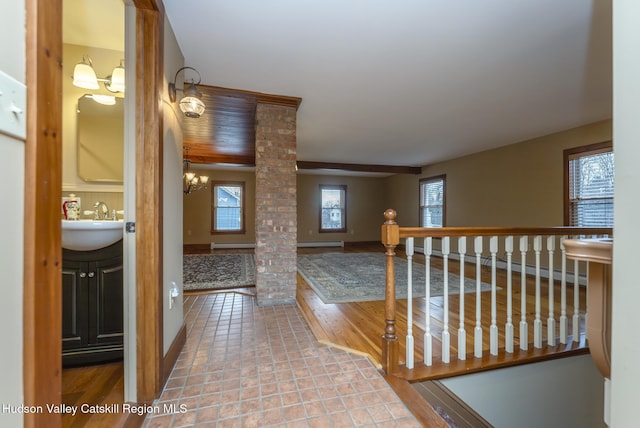 hallway featuring tile patterned flooring, sink, a chandelier, and decorative columns