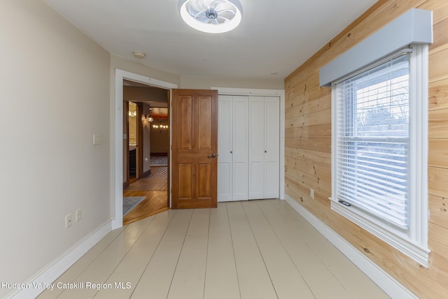 unfurnished bedroom featuring a closet, wood walls, and light hardwood / wood-style flooring