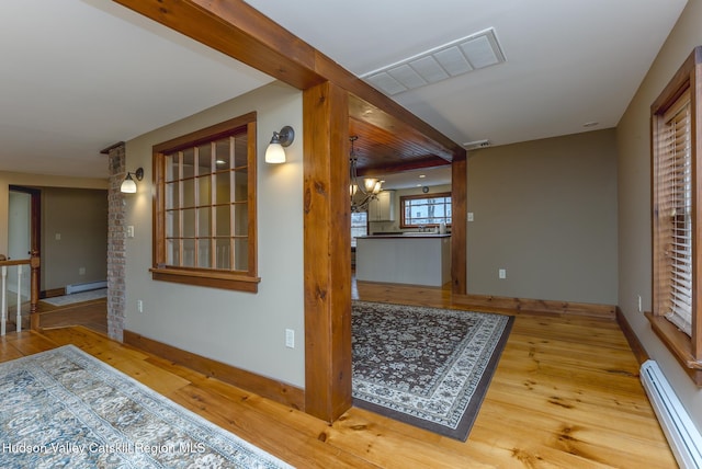 hall with baseboard heating, a chandelier, and hardwood / wood-style flooring