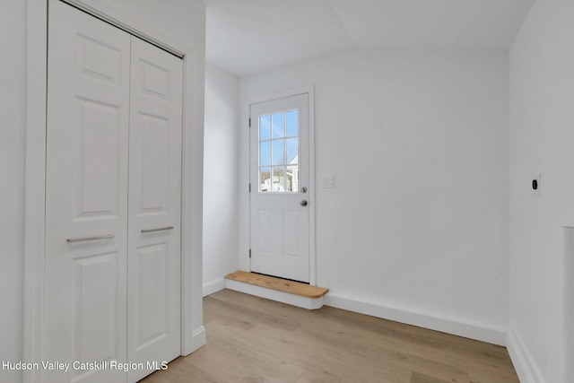 entryway with baseboards, vaulted ceiling, and light wood-style floors