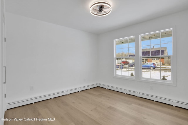 empty room featuring a baseboard radiator and light wood-style flooring