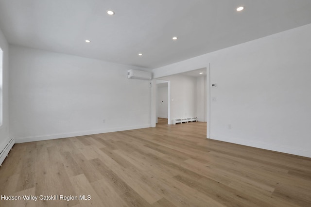 spare room featuring light wood-type flooring, baseboards, and a wall mounted AC