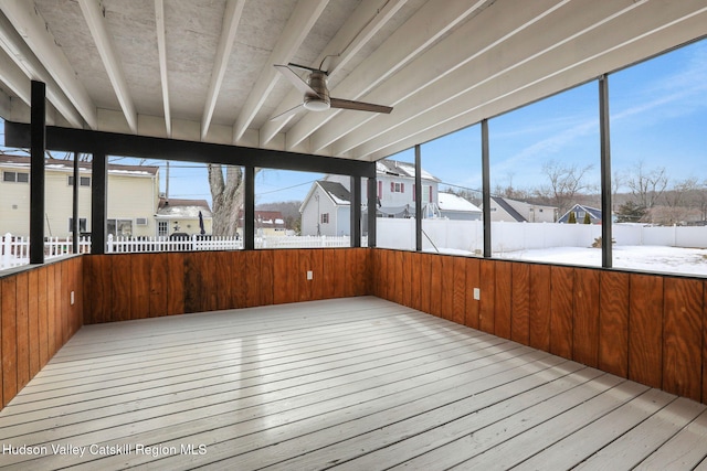 unfurnished sunroom featuring a residential view and a ceiling fan