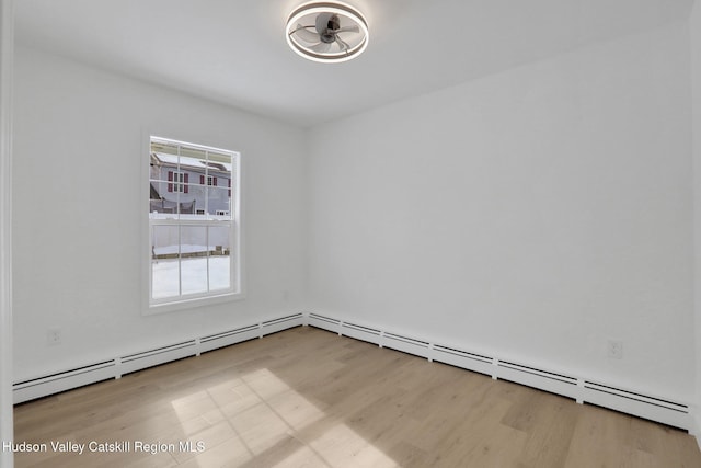 empty room with light wood finished floors and baseboard heating