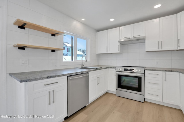 kitchen with dark countertops, under cabinet range hood, appliances with stainless steel finishes, and white cabinets