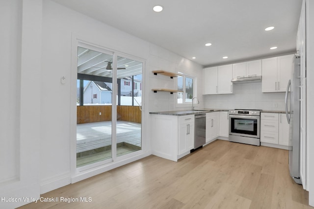 kitchen with appliances with stainless steel finishes, white cabinets, light wood-style flooring, and under cabinet range hood