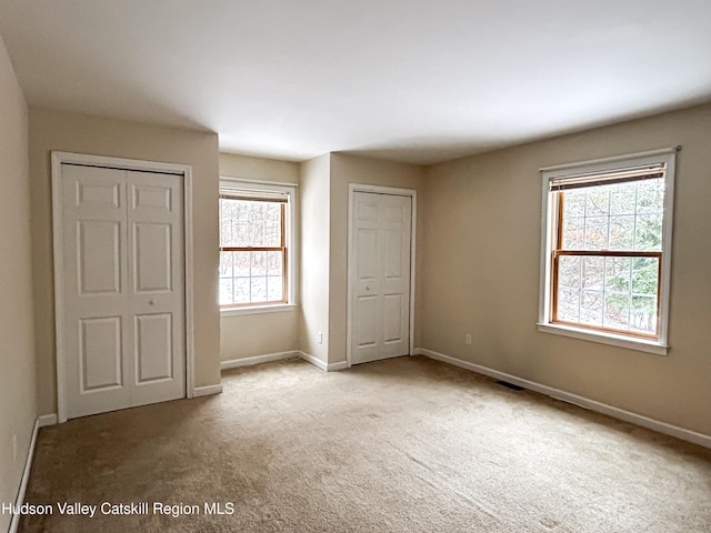 unfurnished bedroom with light colored carpet and multiple windows