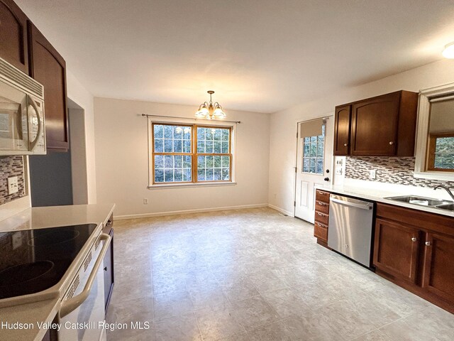 kitchen with sink, stainless steel appliances, a notable chandelier, backsplash, and decorative light fixtures