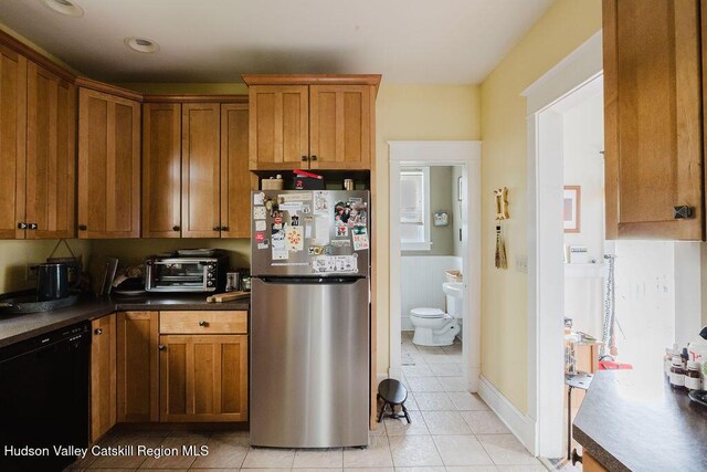 15 Mckinstry Pl, Hudson, NY 12534 - kitchen featuring freestanding refrigerator, black dishwasher, light tile patterned floors, and brown cabinetry