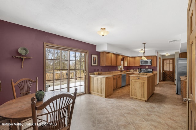 4 Mountain View Dr, Kerhonkson, NY 12446 - kitchen featuring appliances with stainless steel finishes, light countertops, a center island, decorative light fixtures, and brown cabinetry