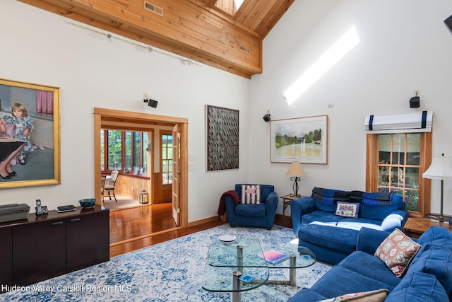 living room with hardwood / wood-style floors, a skylight, high vaulted ceiling, and wooden ceiling