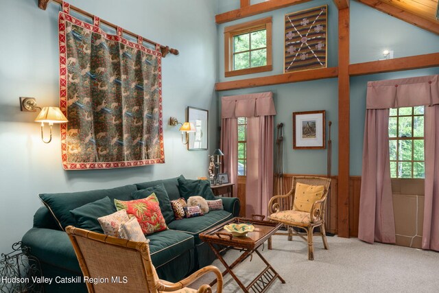 living room with carpet flooring, high vaulted ceiling, a healthy amount of sunlight, and beam ceiling