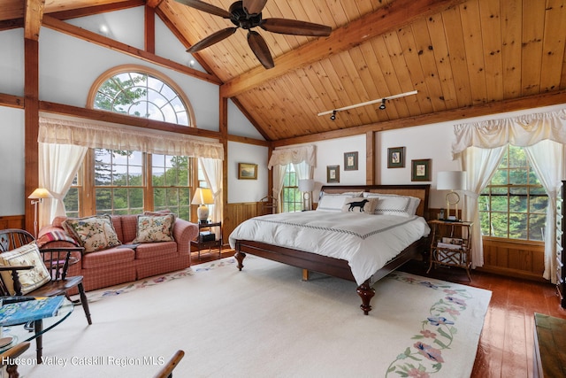 bedroom with hardwood / wood-style floors, wood walls, and multiple windows