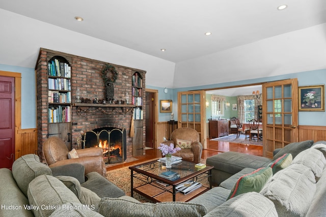 living room with hardwood / wood-style floors, wood walls, a fireplace, and vaulted ceiling