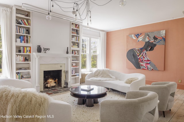 131 William St, Catskill, NY 12414 - living area with a fireplace, built in features, wood finished floors, and radiator heating unit