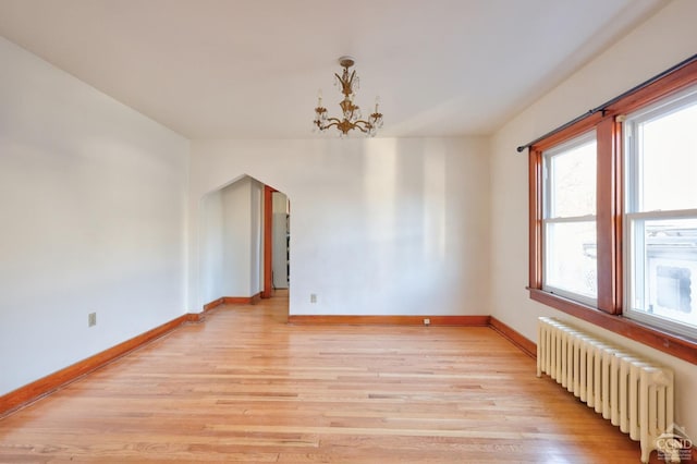 825 Union St, Hudson, NY 12534 - empty room featuring radiator heating unit, light wood finished floors, arched walkways, and baseboards