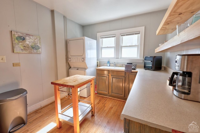 825 Union St, Hudson, NY 12534 - kitchen with stacked washer and clothes dryer, open shelves, light countertops, brown cabinets, and light wood-type flooring
