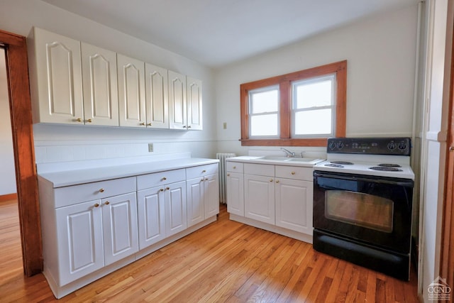 825 Union St, Hudson, NY 12534 - kitchen with electric stove, light wood-style floors, white cabinets, and a sink