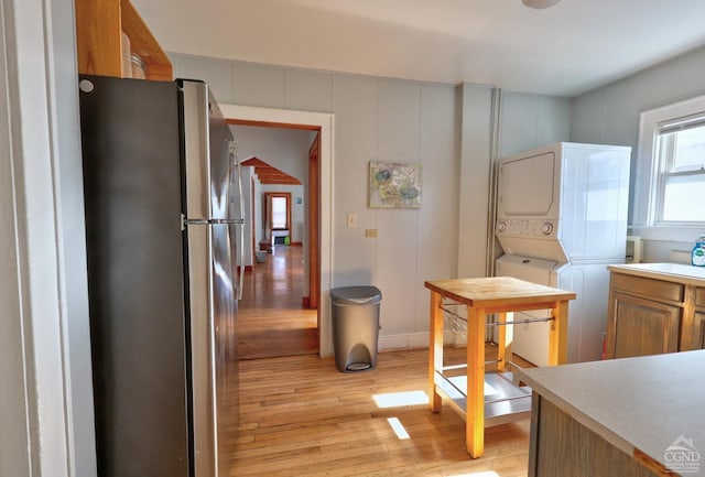 825 Union St, Hudson, NY 12534 - kitchen with freestanding refrigerator, stacked washer / dryer, light wood-type flooring, light countertops, and brown cabinetry