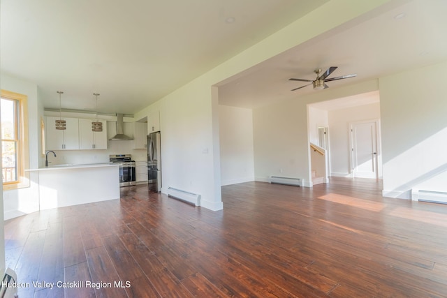 unfurnished living room featuring a baseboard heating unit, a sink, ceiling fan, and dark wood-style floors