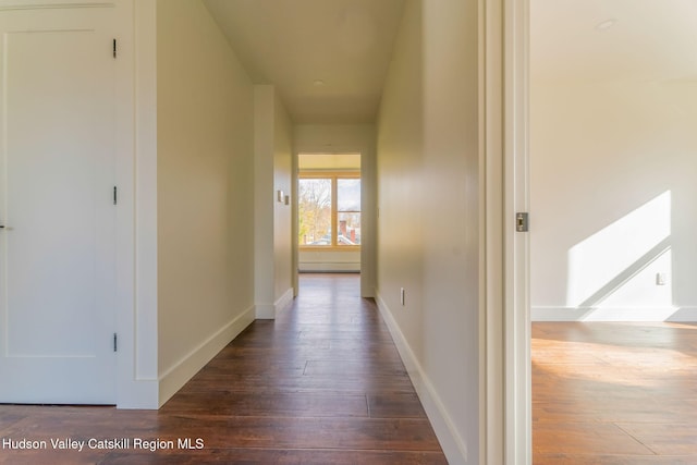 hallway featuring dark wood-type flooring and baseboards