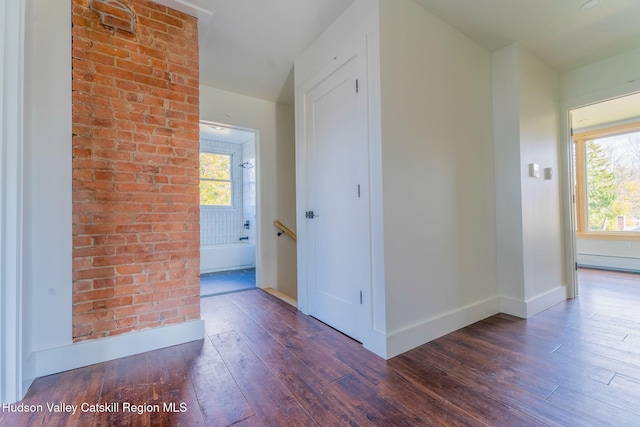 hall with brick wall, baseboards, and hardwood / wood-style floors