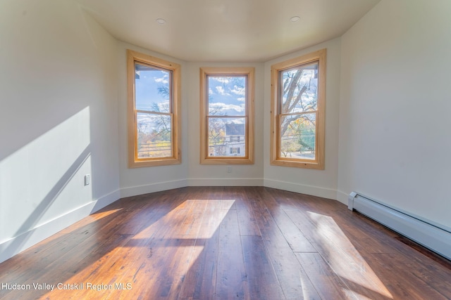 unfurnished room featuring wood-type flooring, baseboards, and baseboard heating