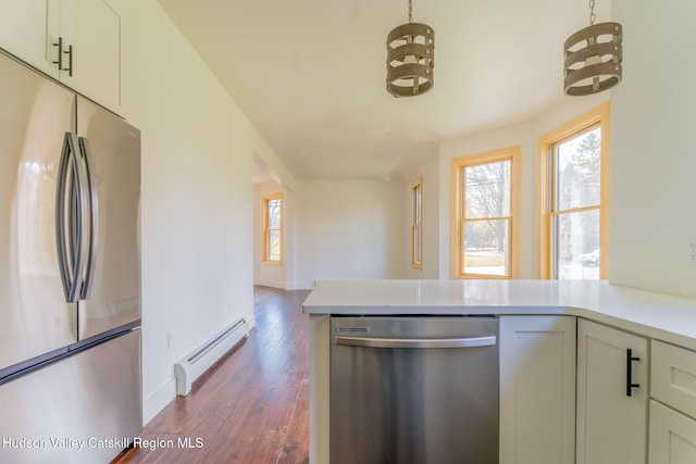 kitchen featuring light countertops, appliances with stainless steel finishes, baseboard heating, and a healthy amount of sunlight