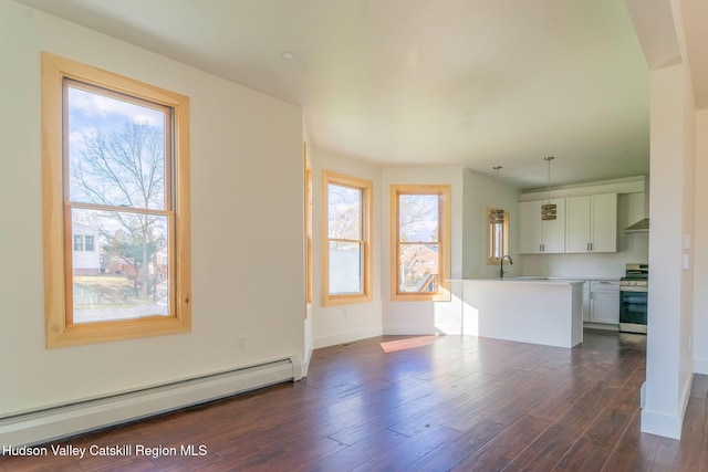 unfurnished living room with a baseboard heating unit, dark wood-style flooring, plenty of natural light, and a sink