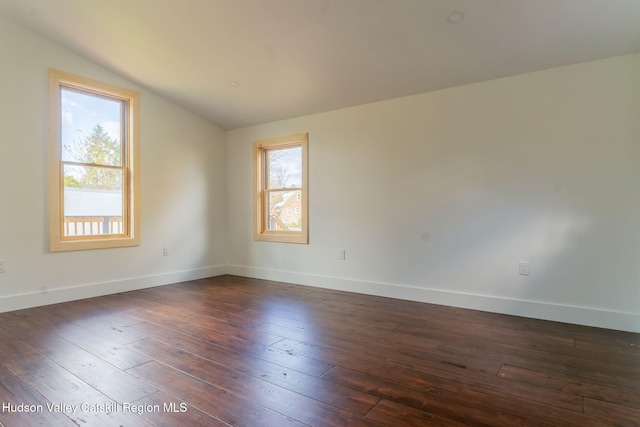 unfurnished room with dark wood-style floors, vaulted ceiling, and baseboards