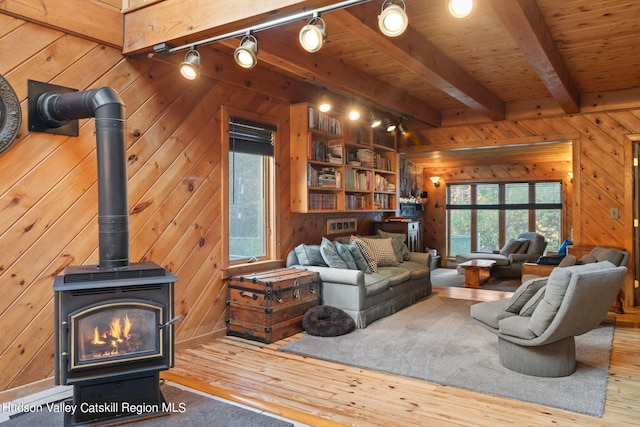 living room featuring wood-type flooring, track lighting, a wood stove, and wood walls